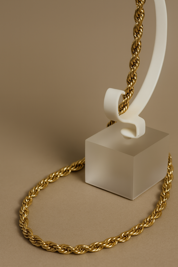Gold chain on a white stand against a beige background