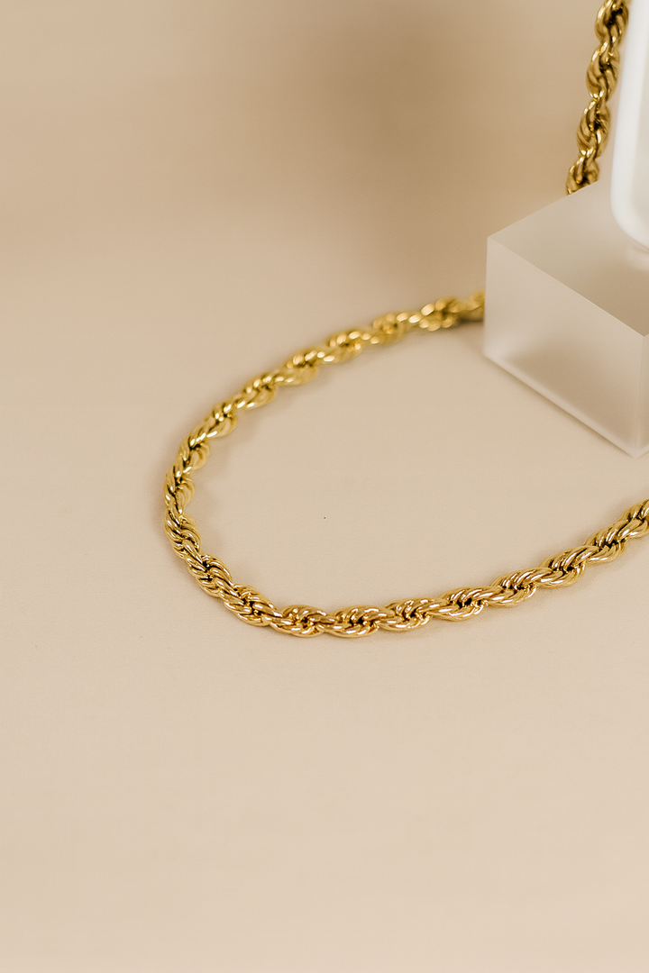 Gold chain necklace on a beige background