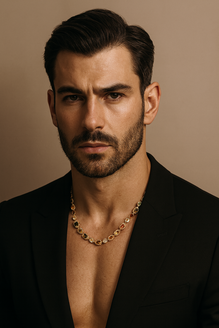 Man wearing a black suit and gold chain necklace against a beige background