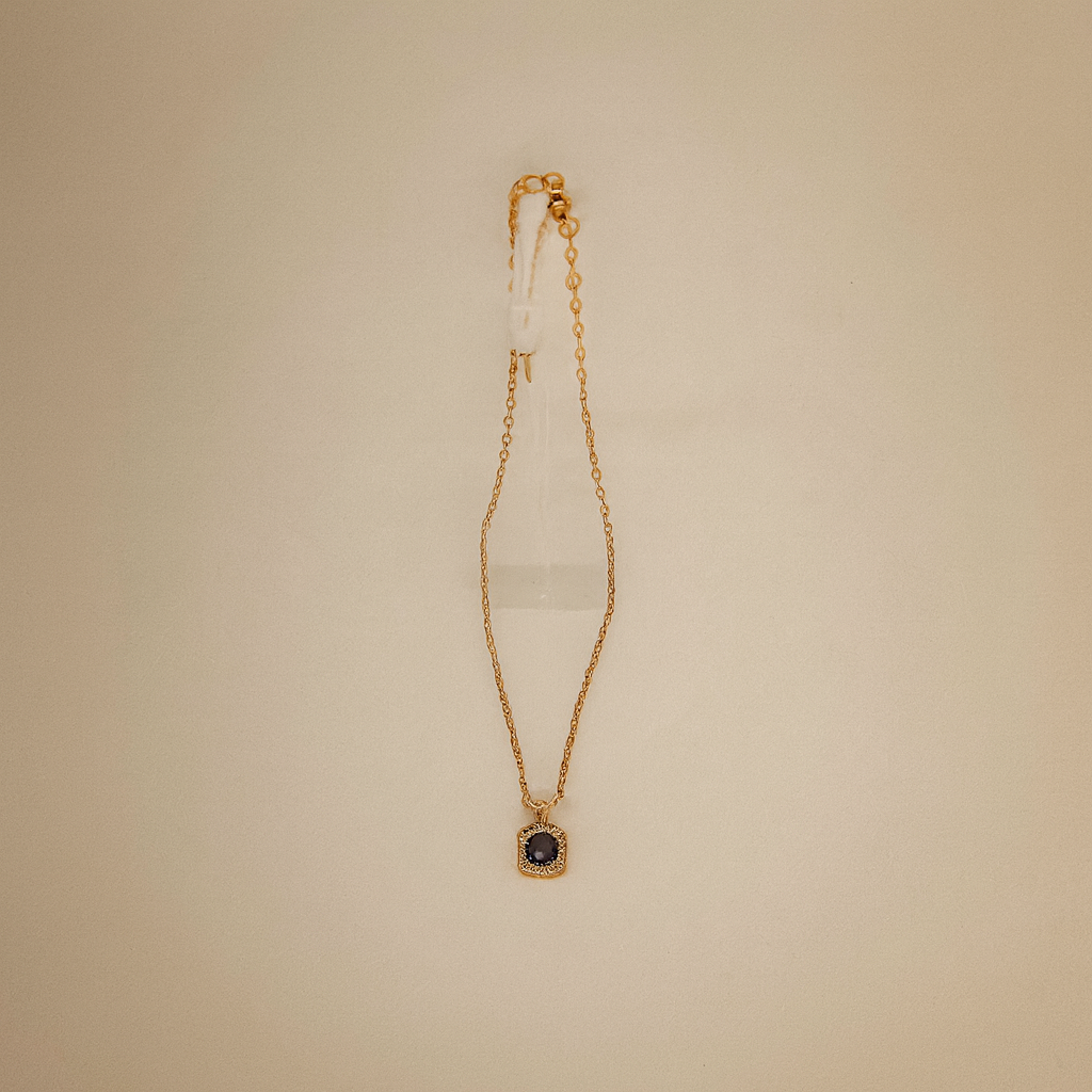 Gold necklace with a pendant on a beige background